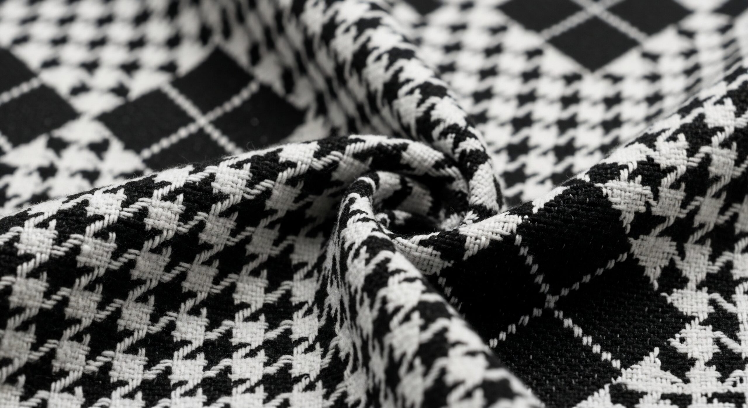 Detailed view of a black and white houndstooth pattern fabric, showing its woven texture and folded layers.